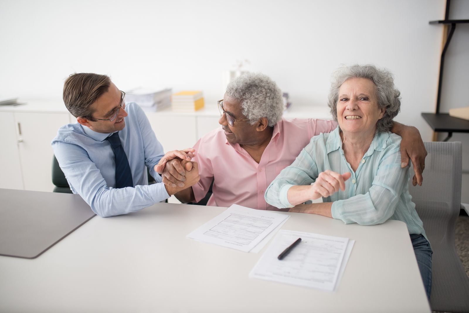 An older couple meeting with an agent at a bright table